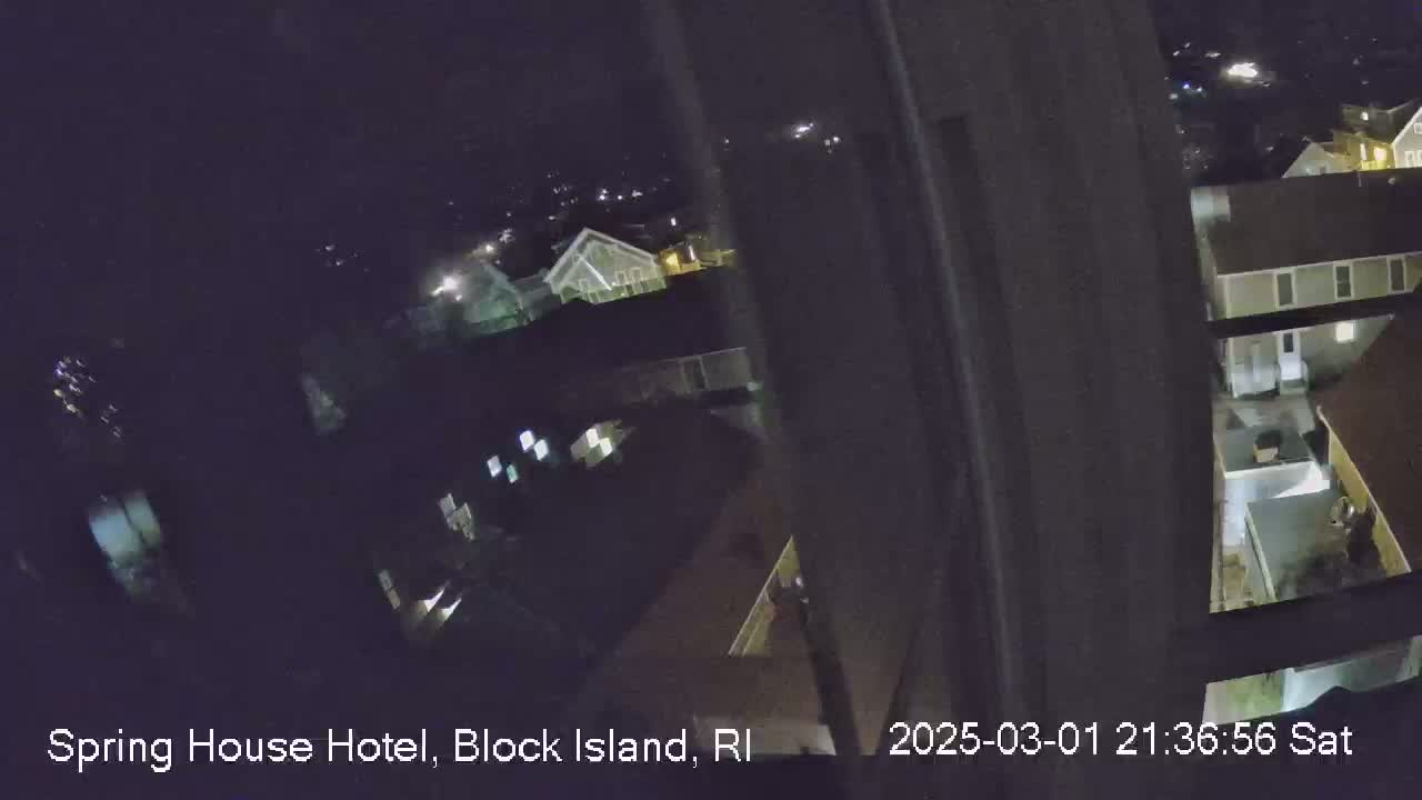 A nighttime view from a window shows a dimly lit residential area with several buildings.