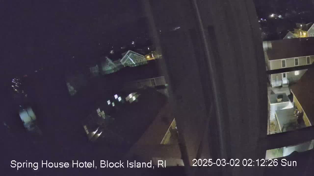 A nighttime, high-angle view from a window shows several illuminated buildings.