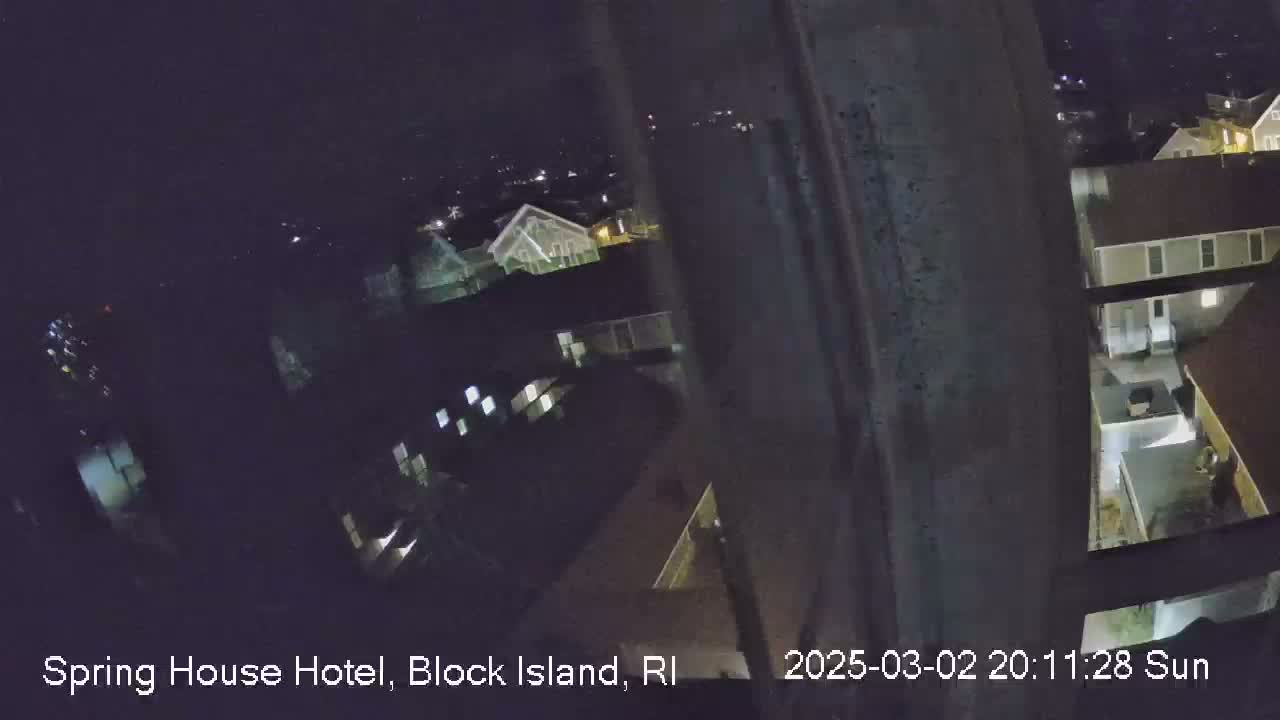 A nighttime, high-angle view shows a section of a town with several buildings, some with lights on.