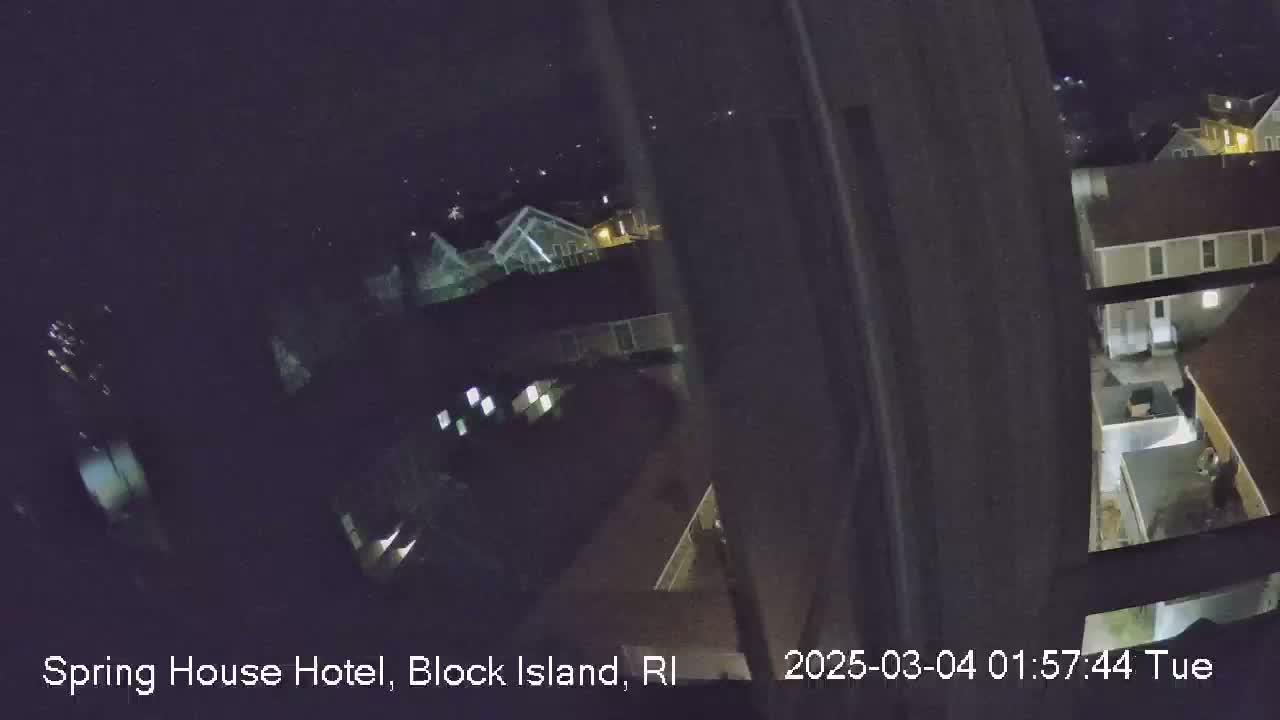 A nighttime, high-angle view shows a cluster of buildings with some lights on.