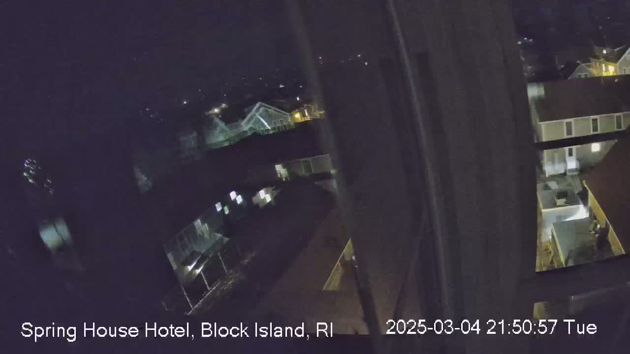 A nighttime, high-angle view from a window shows several buildings and a parking lot.