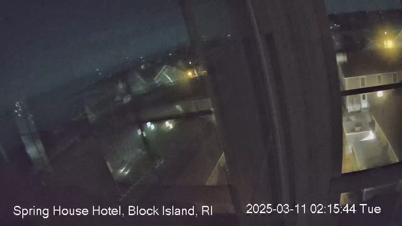 A nighttime view from a window shows dimly lit buildings and grounds under a dark sky.