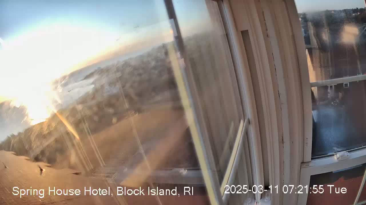 A sunrise view through a slightly dirty window shows a hazy, distant coastline.