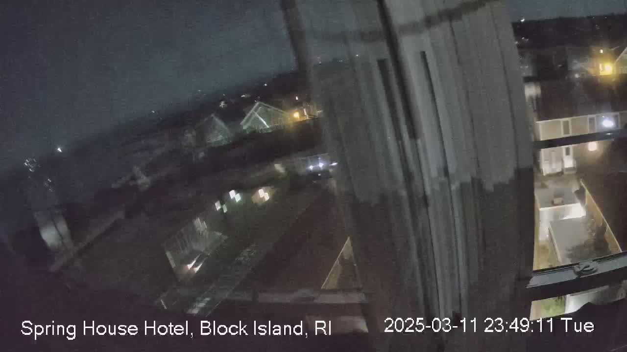 A nighttime, blurry view from a window shows a dimly lit residential area.