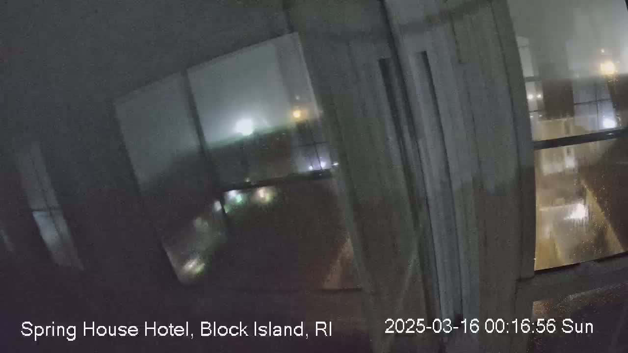 A nighttime view of rain-streaked windows showing blurry lights and buildings outside.