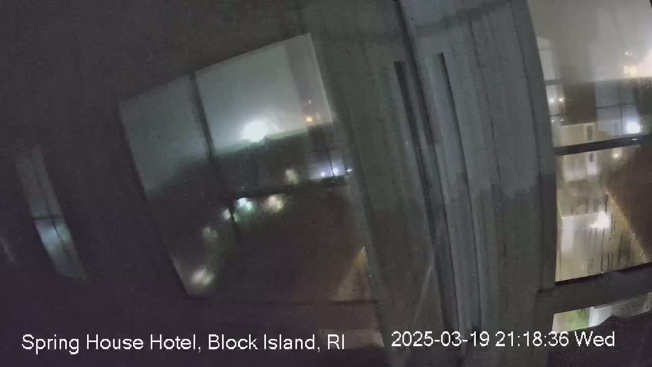 A nighttime view through a rain-streaked window shows blurry, indistinct lights and buildings outside.