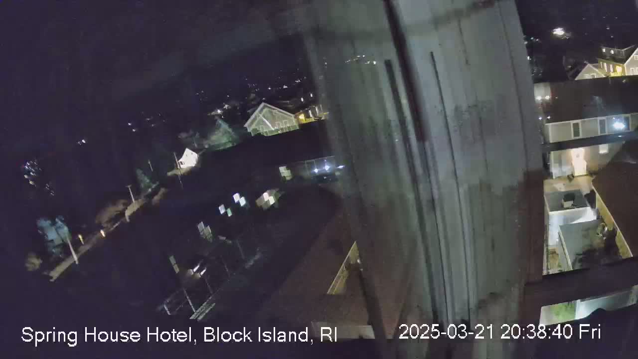 A nighttime, high-angle view from a window shows a residential area with houses and streets.