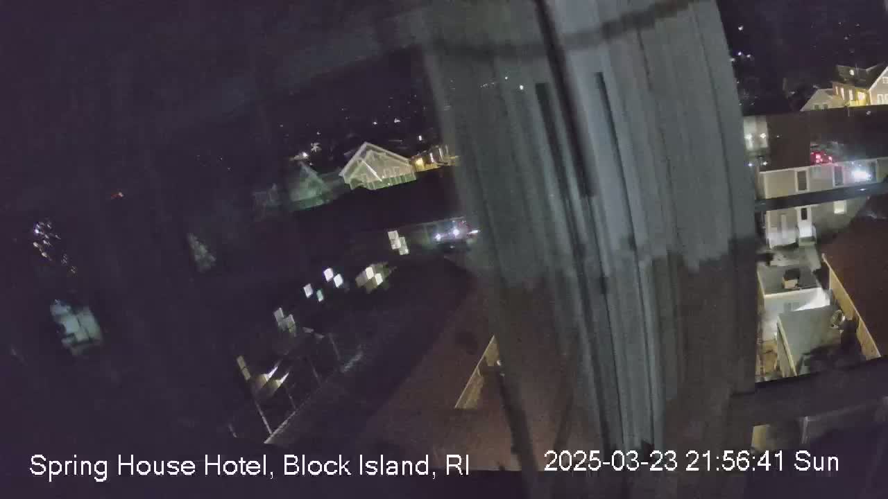 A nighttime, high-angle view from a window shows a dark residential area with some buildings lit up.