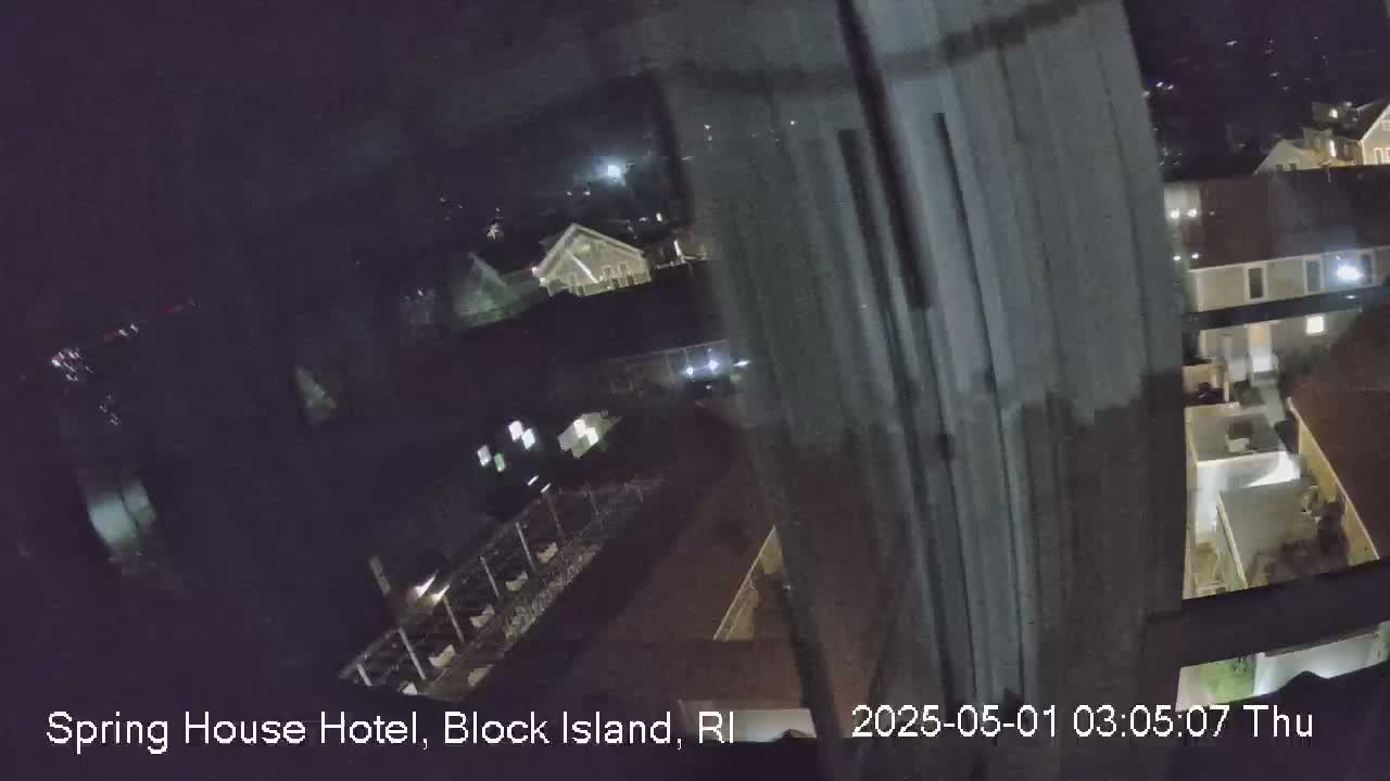 A nighttime view from a window shows a dimly lit residential area with several buildings.