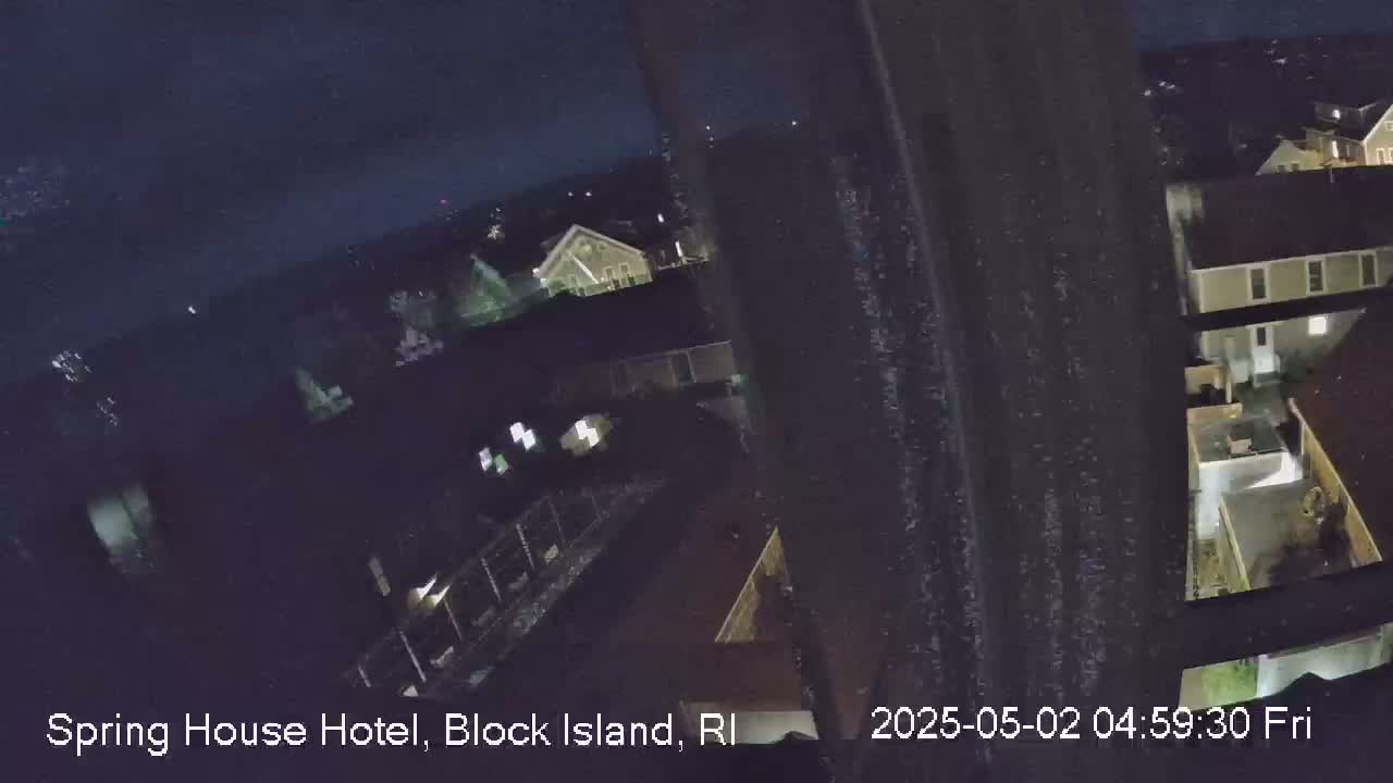 A nighttime, high-angle view shows several houses and yards, possibly from a rooftop.
