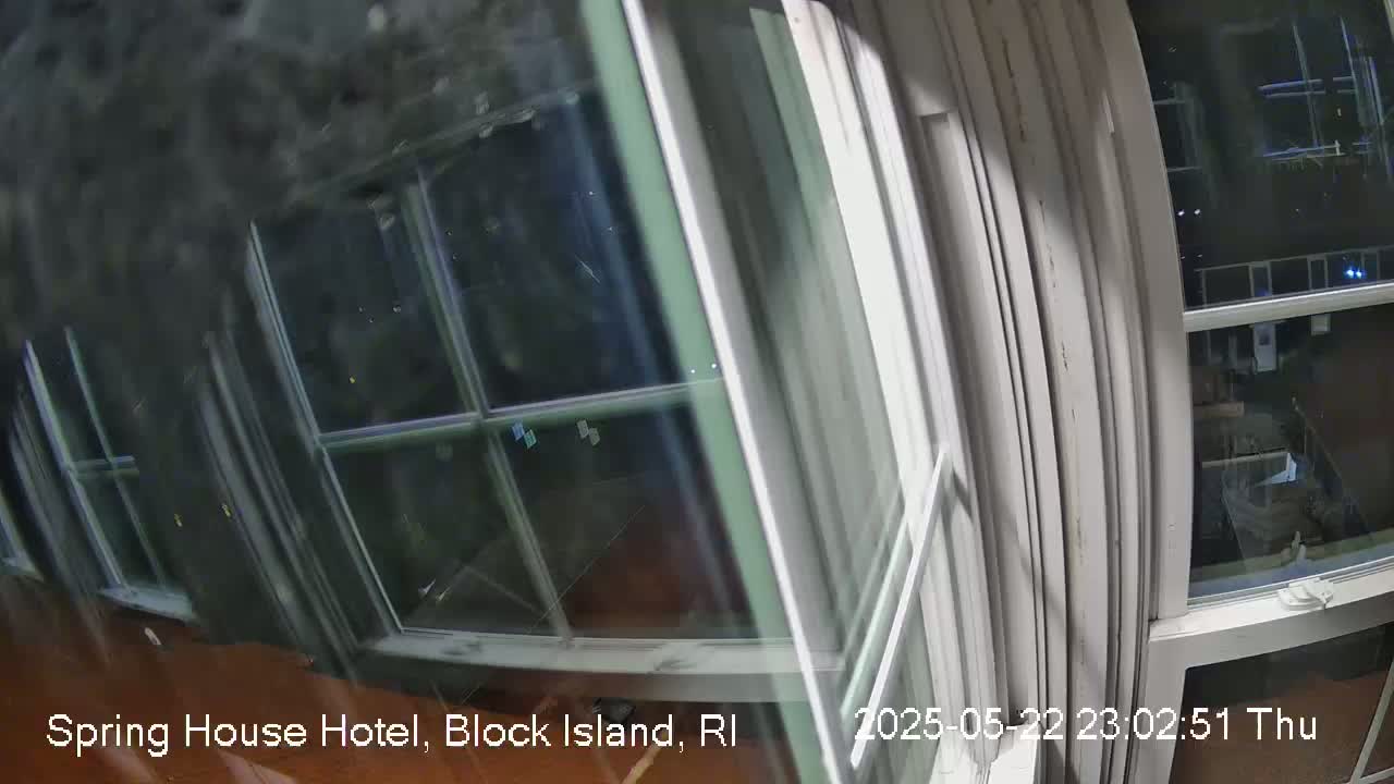 A nighttime view from inside a room shows a window with multiple panes reflecting blurry outdoor lights.
