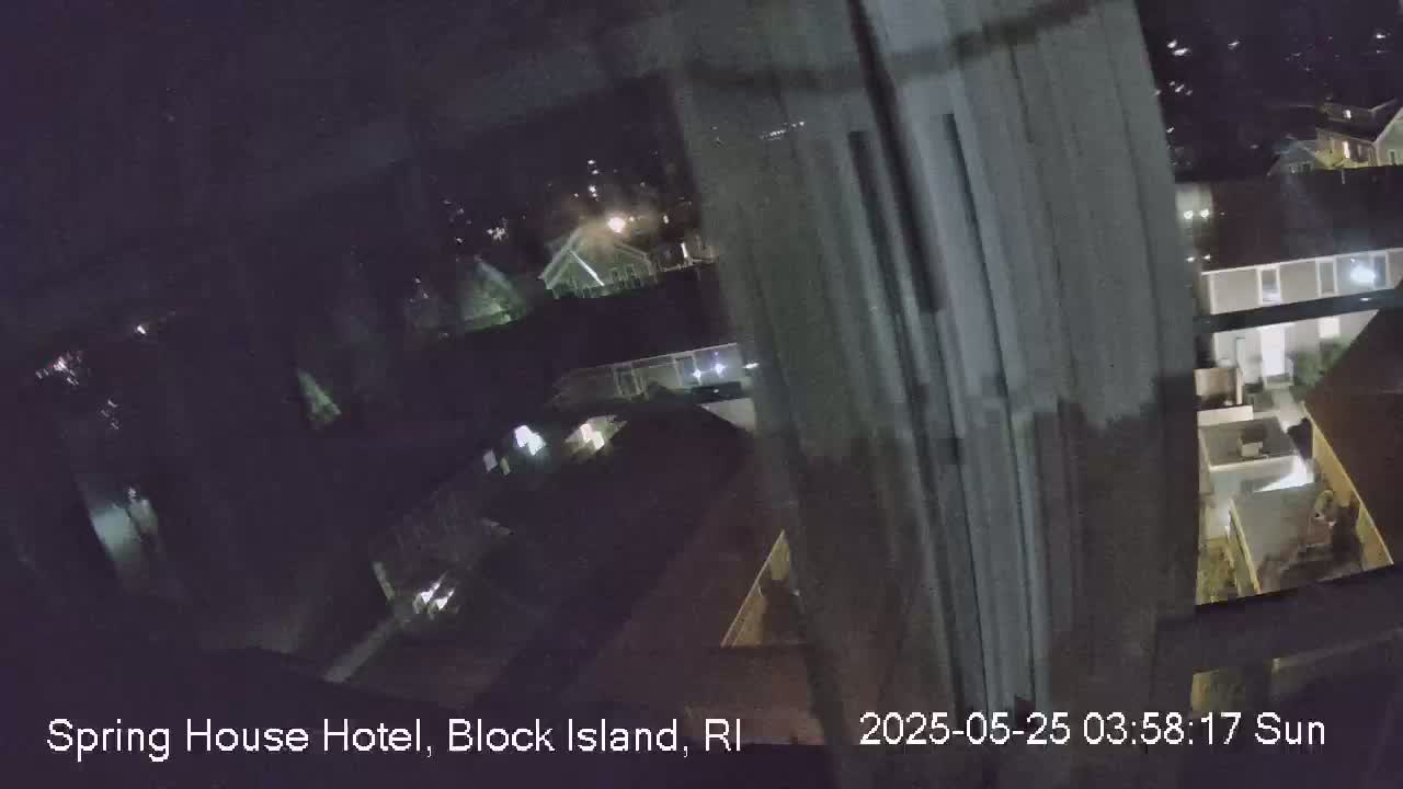 A nighttime, blurry view from a window shows several houses with some lights on.