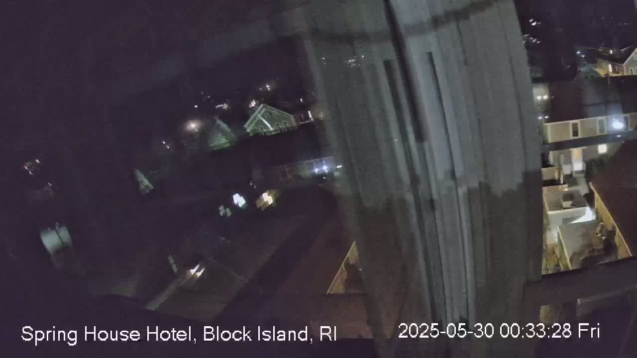 A nighttime, blurry view from a window shows dimly lit houses and streets.