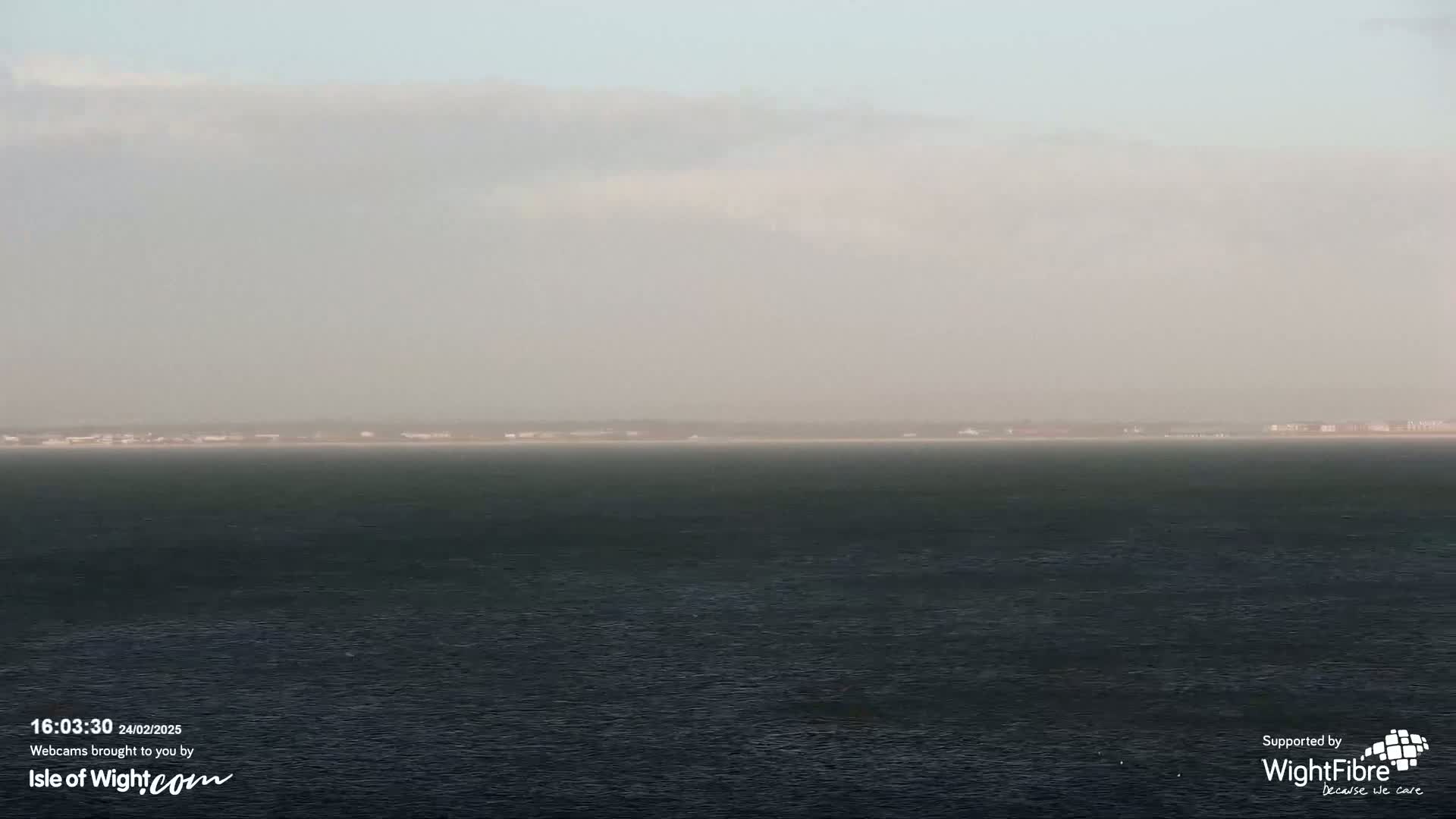 A hazy, overcast day reveals a dark expanse of water stretching to a distant, indistinct shoreline.