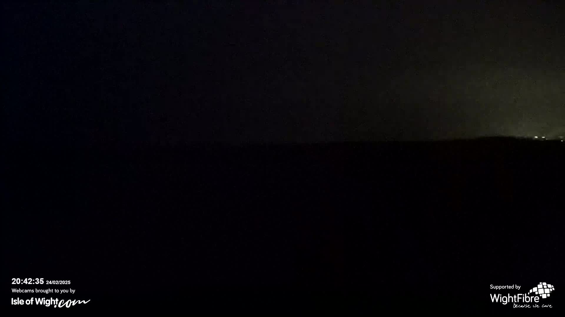 A dark, nighttime landscape is visible under a slightly hazy sky.