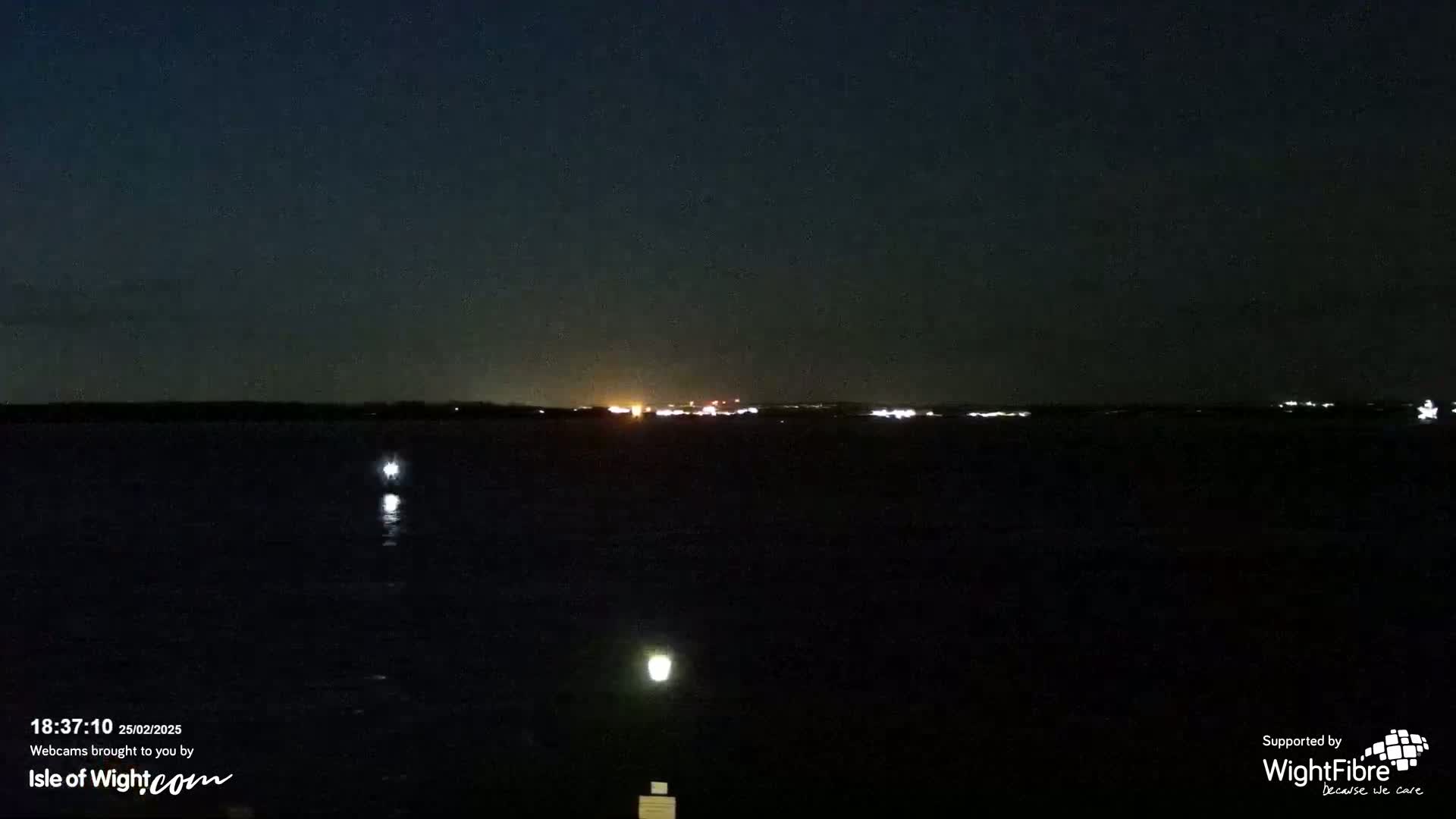 A dark, nighttime view of a body of water with distant lights on the horizon.