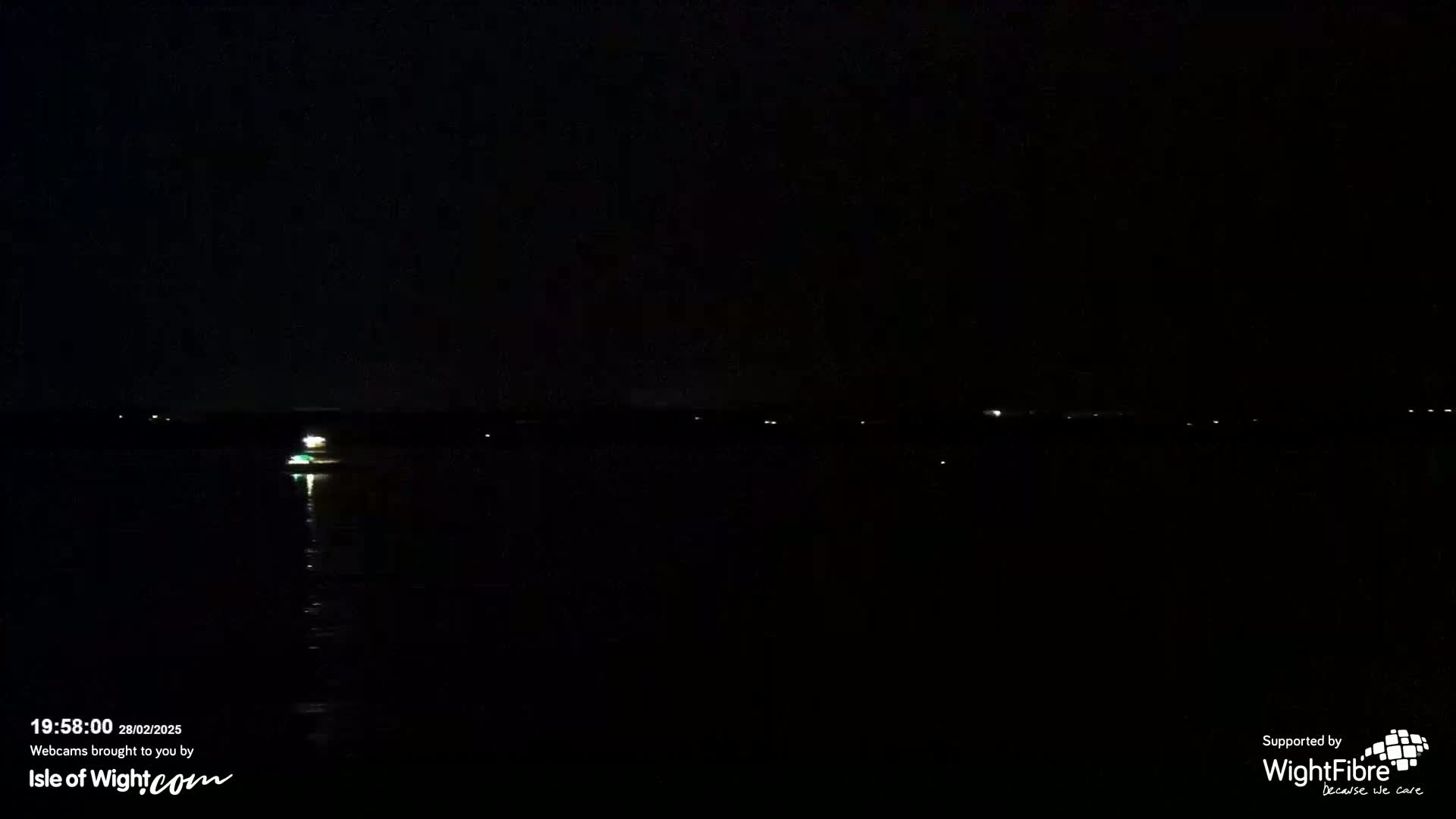 A dark, nighttime view of a body of water with a few distant lights visible on the opposite shore.