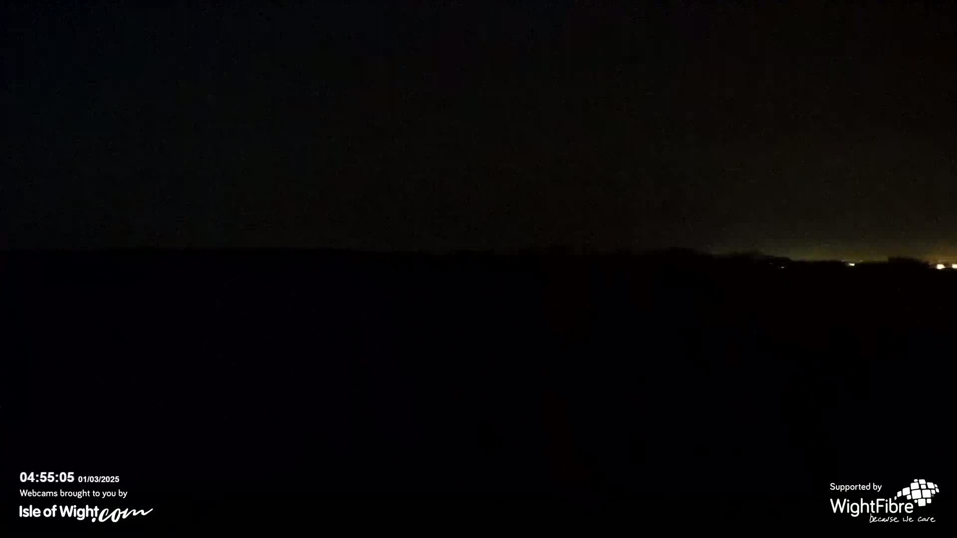 A dark, nighttime landscape is visible, with a faint glow of lights on the horizon.
