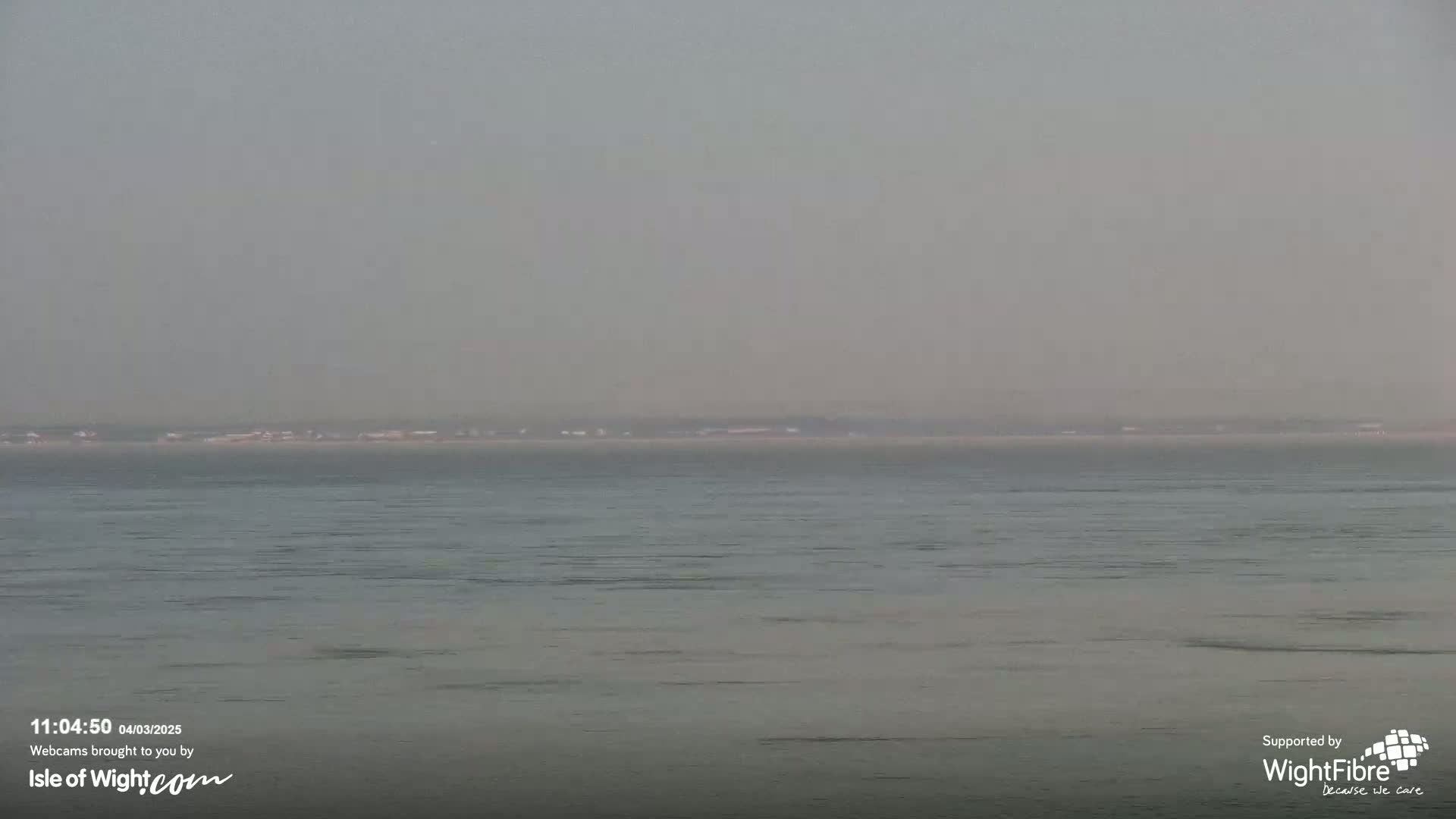 A hazy, calm body of water stretches to a distant, indistinct shoreline.