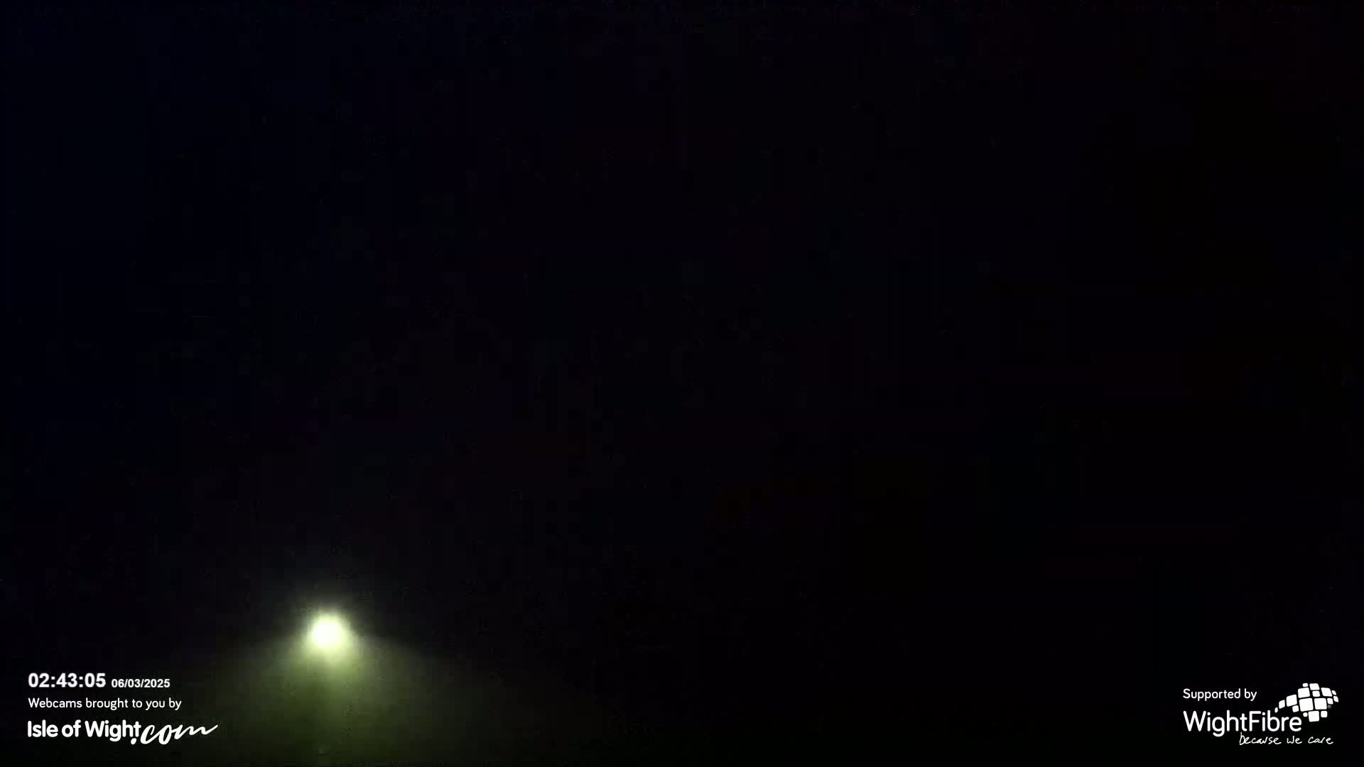 A bright light shines through a dark, foggy night.