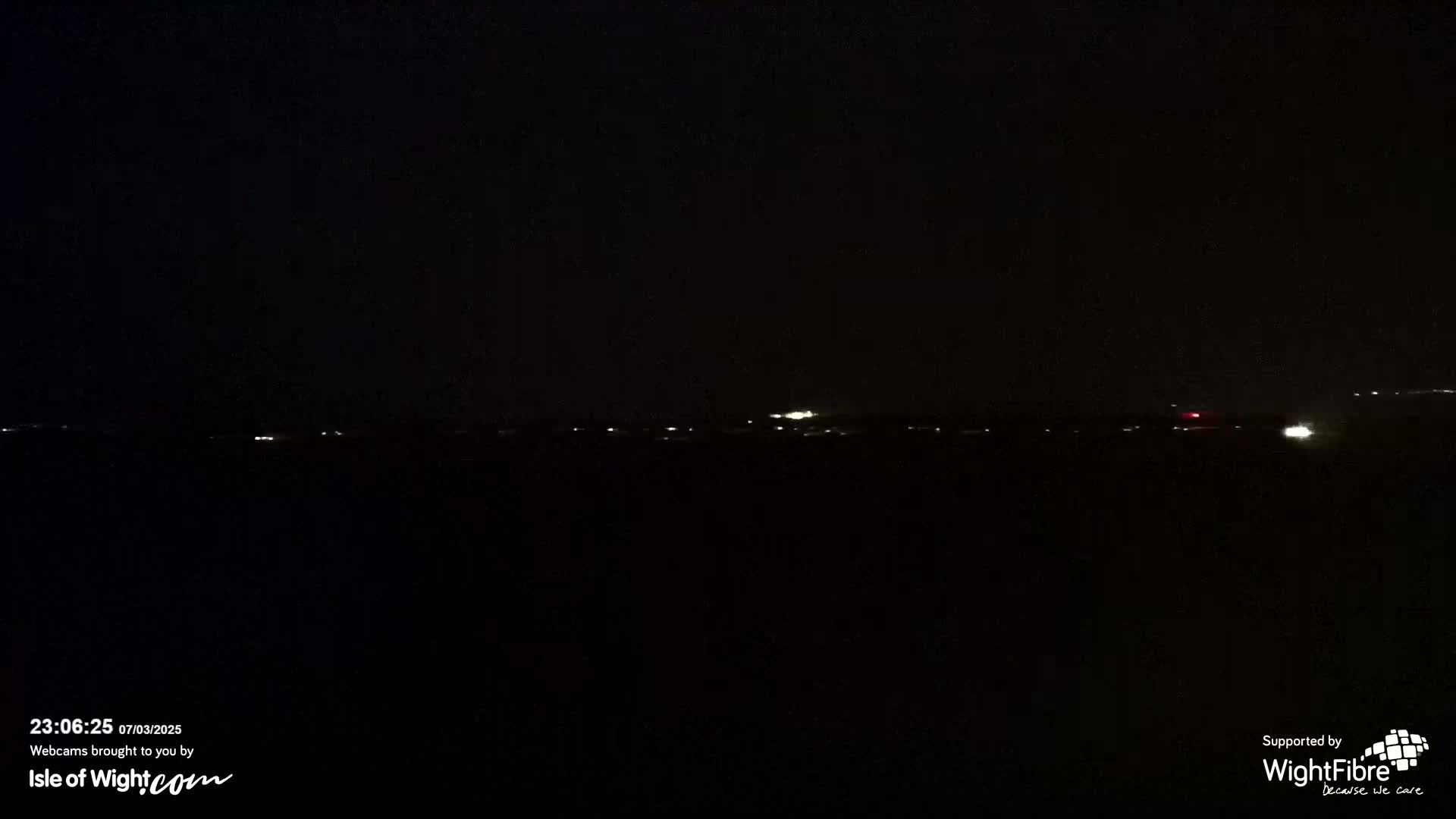 A dark, nighttime scene shows a distant horizon line with a few faint lights visible.