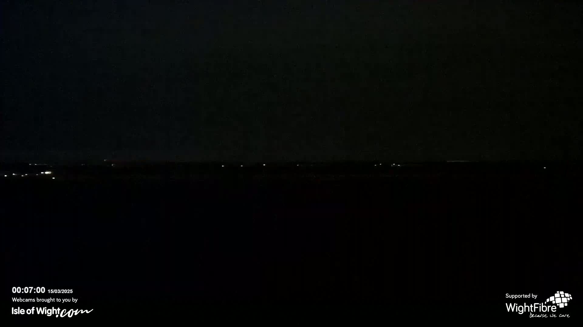 A dark, nighttime landscape is visible, featuring a few faint lights on the horizon.