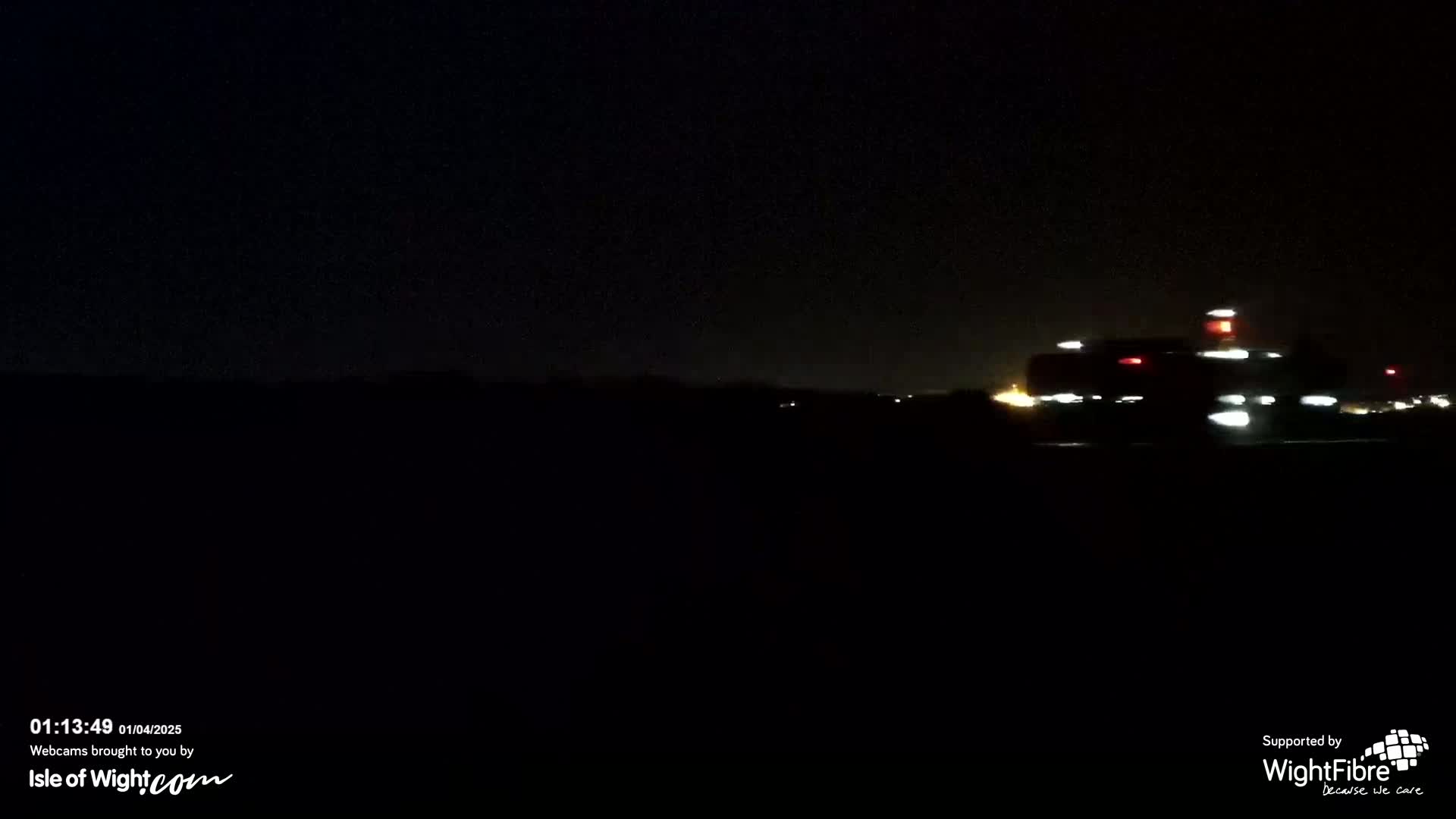 At night, a vehicle with lights is visible in the distance, traveling across a dark landscape under a clear, dark sky.