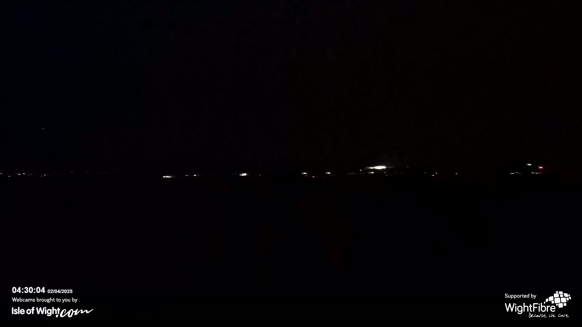 A dark, nighttime landscape shows a faint line of distant lights on the horizon.