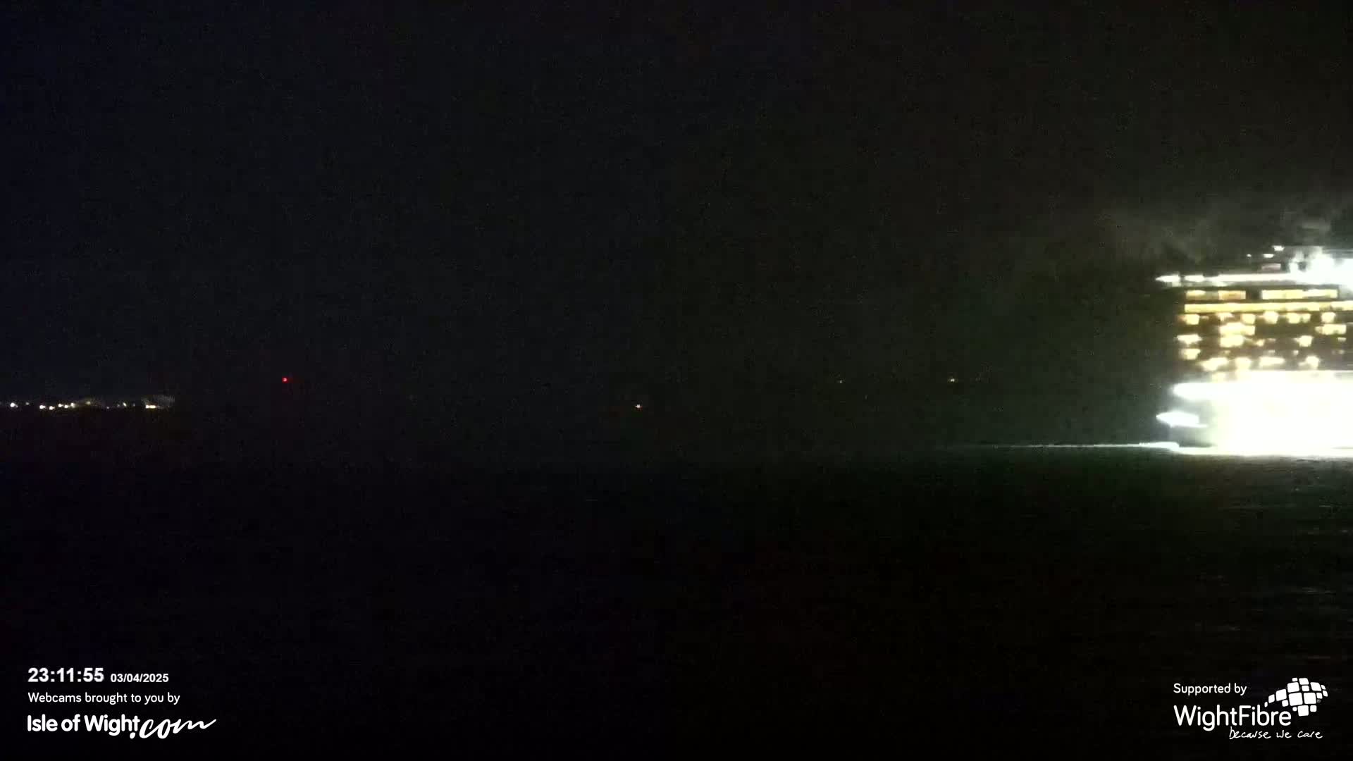 A large, brightly lit cruise ship is visible on the dark ocean at night.