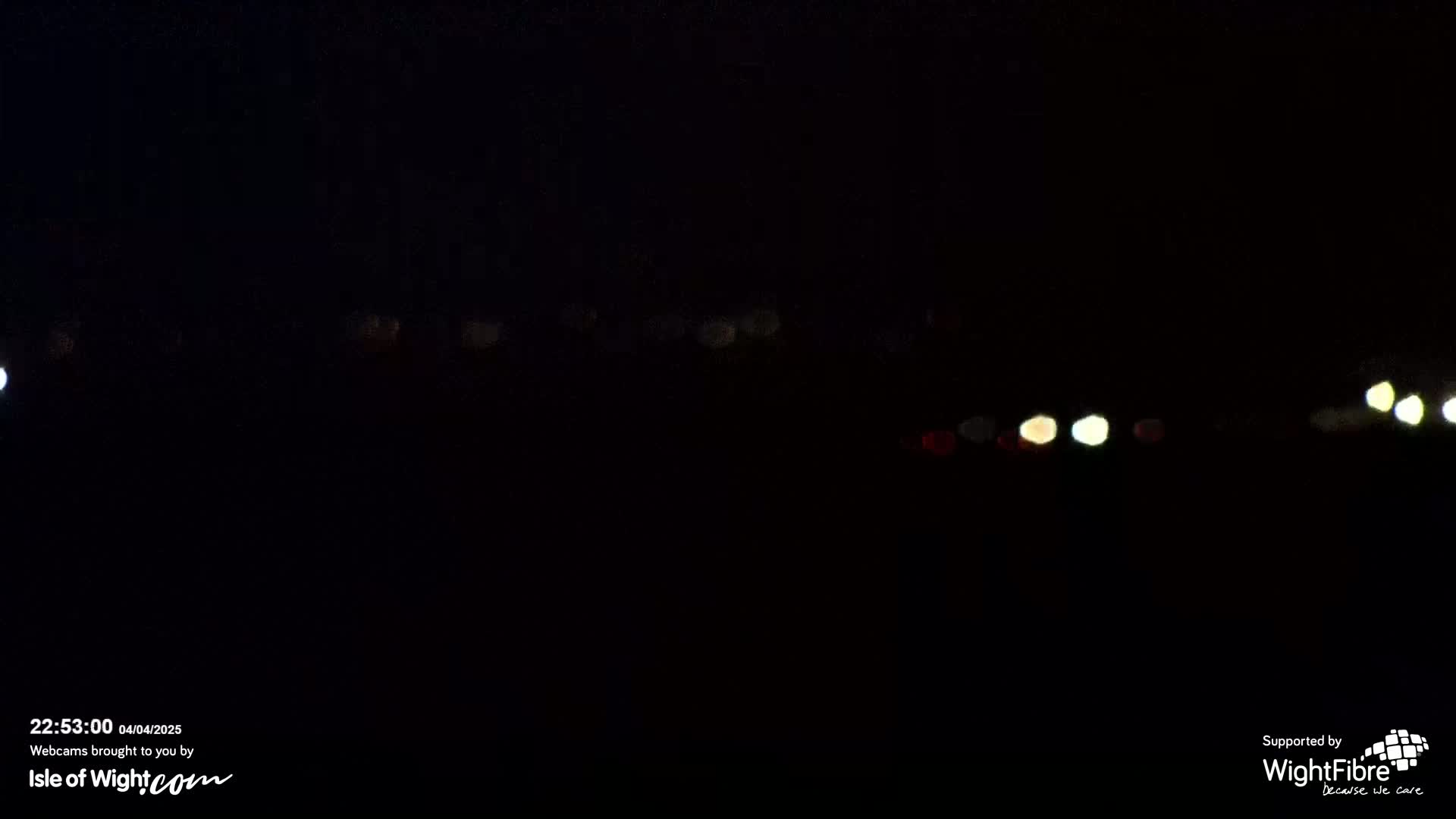 A dark, nighttime scene shows a blurry line of distant lights.