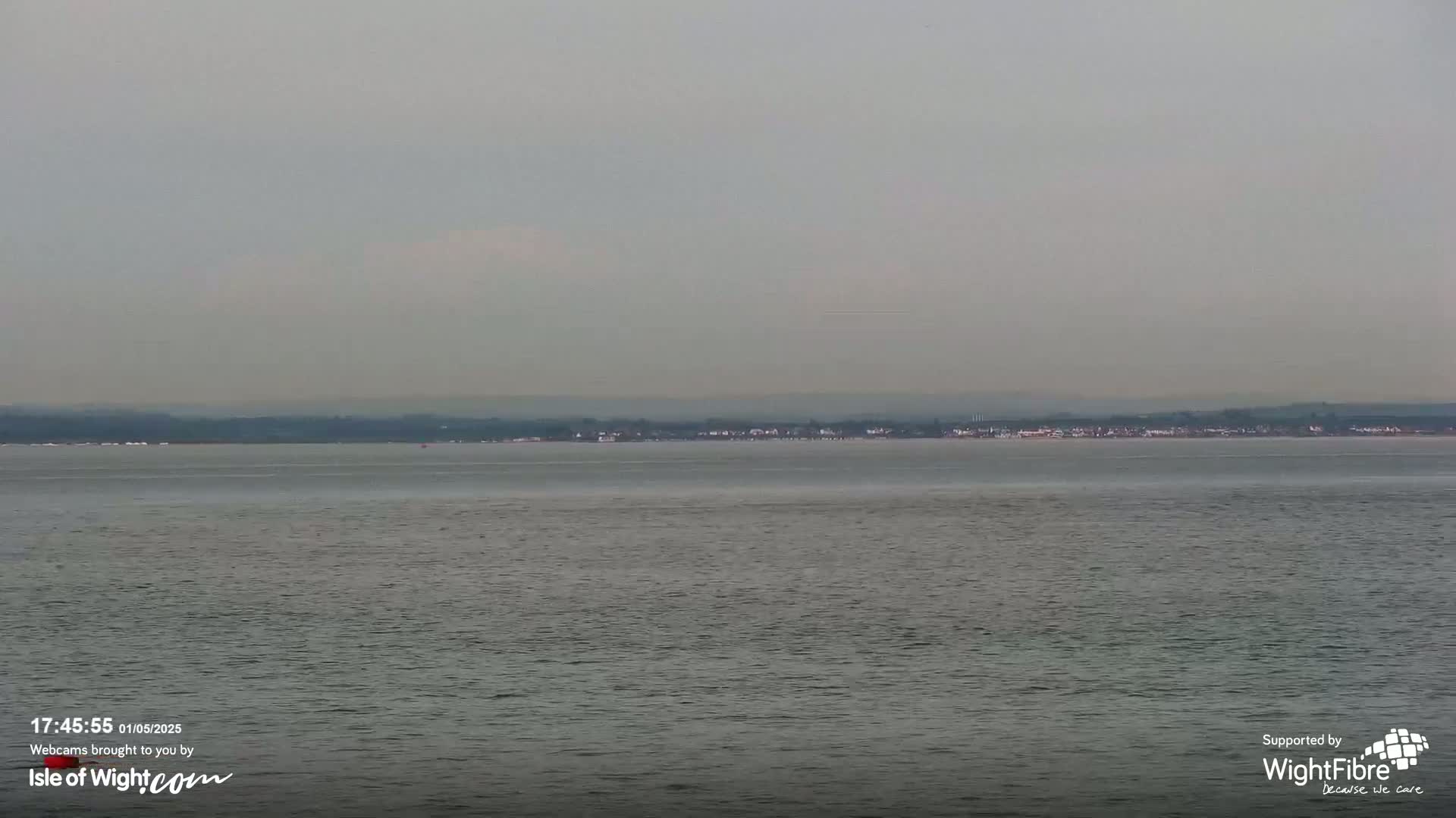A calm, gray day shows a body of water with a distant shoreline.