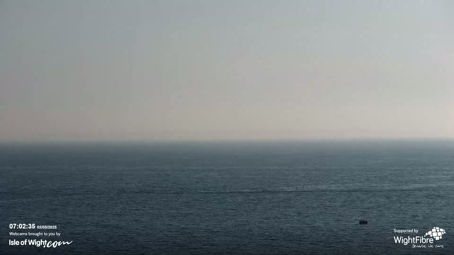 A hazy, calm sea stretches to a pale horizon under a muted sky.
