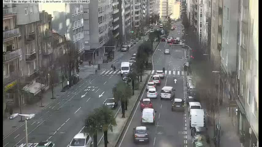 A city street scene with several cars driving in both directions on a grey day.