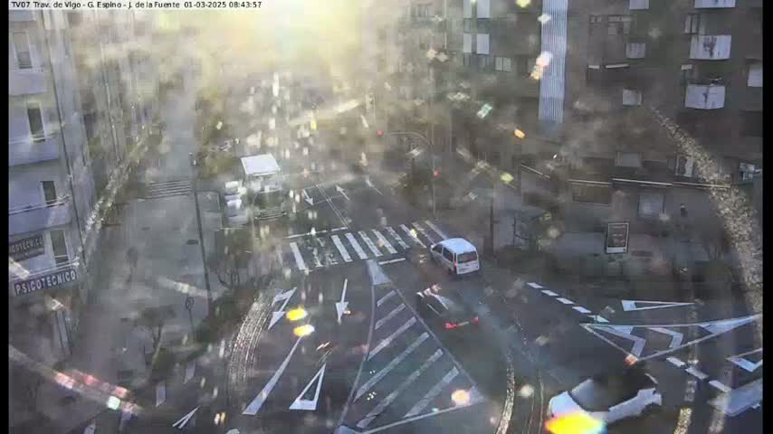 A rainy day view from above shows a city intersection with several cars and buildings visible, some buildings appearing partially obscured by rain and glare.