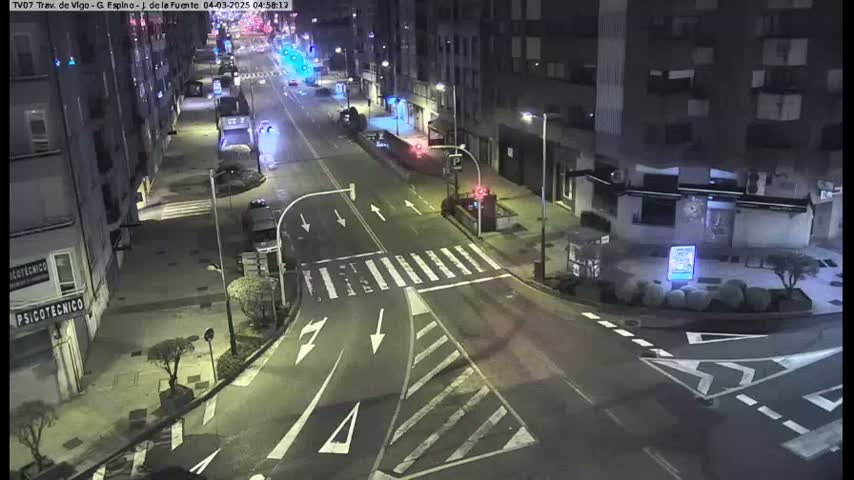A nighttime, mostly empty street intersection with several buildings visible under artificial light.