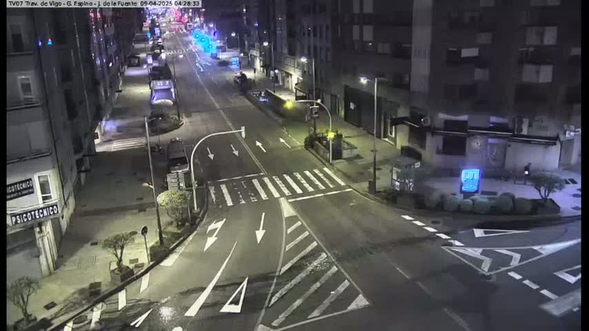 A nighttime street intersection with minimal traffic, under clear skies.