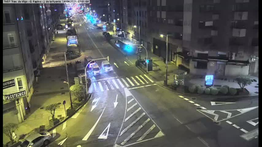A nighttime, high-angle view of a mostly empty city street intersection with a few cars and buildings.