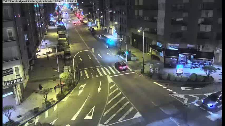 A nighttime, aerial view of a city intersection with several cars and buildings under streetlights.