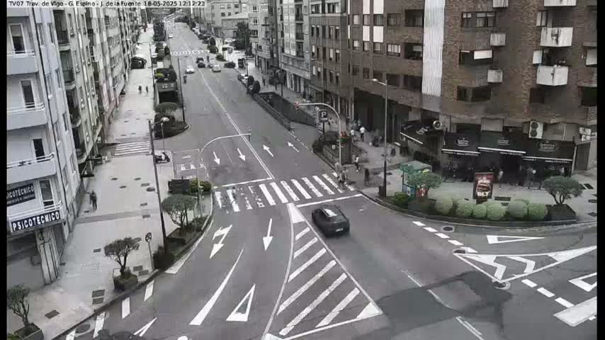 A street intersection in a city, with several buildings and cars, on an overcast day.