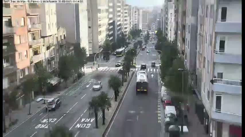 A street scene shows several multi-story buildings lining a city street with moderate traffic under an overcast sky.