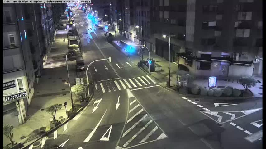 A nighttime, street-level view of a mostly empty intersection with several buildings lining the streets and sparse traffic.