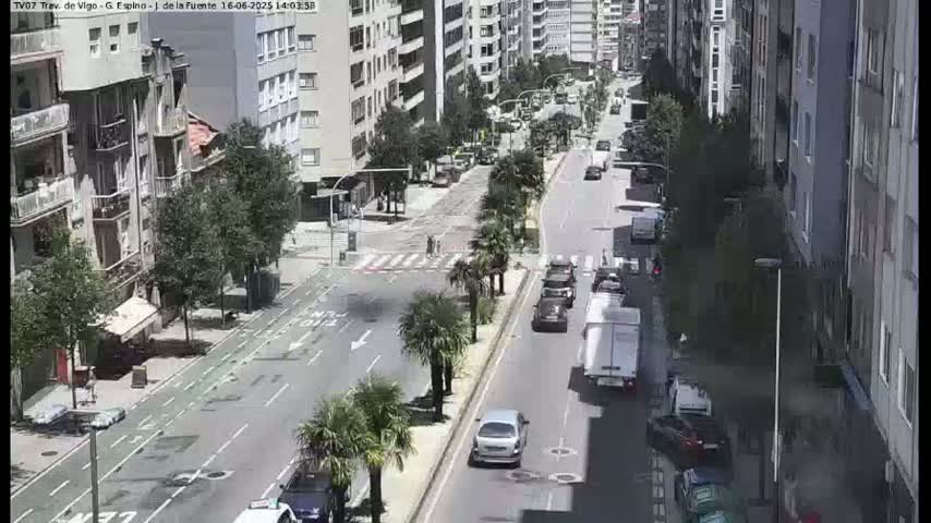 A sunny city street scene shows several cars driving on a multi-lane road lined with tall buildings and palm trees.