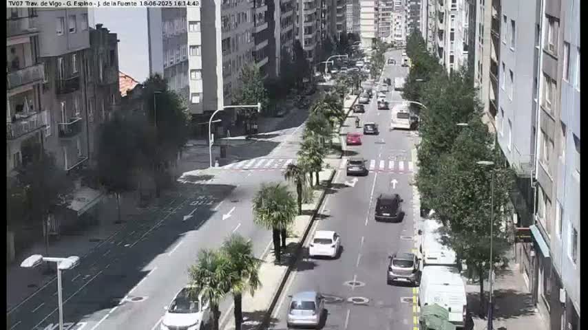 A sunny city street scene shows several cars driving in both directions along a road lined with palm trees and tall buildings.