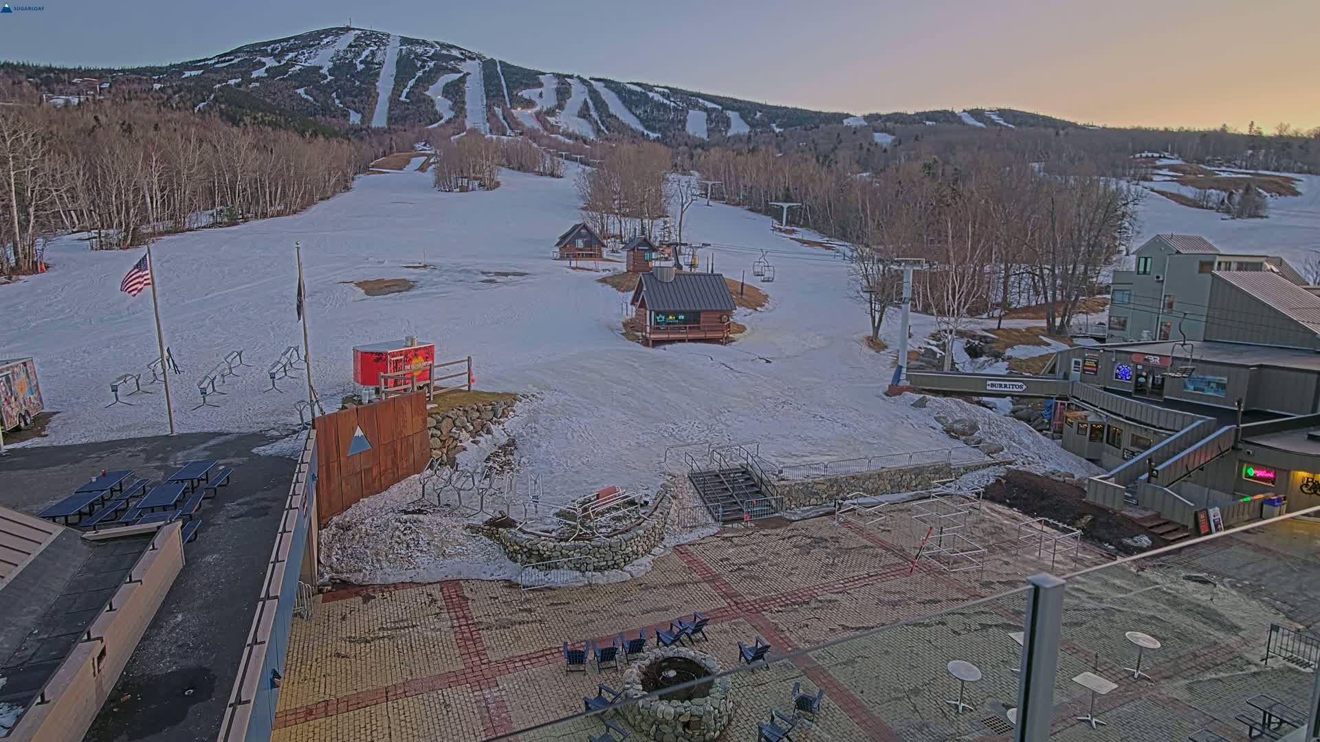 A snow-covered ski resort with several buildings and ski lifts, under a twilight sky.