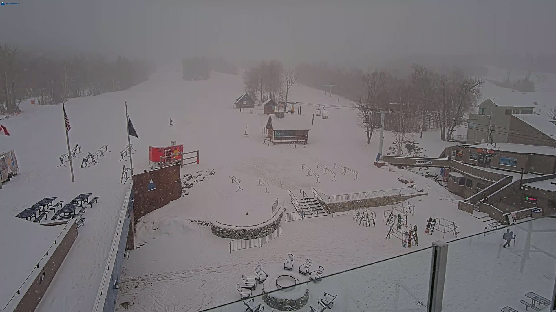 A snow-covered ski resort is viewed from above during a heavy snowfall.