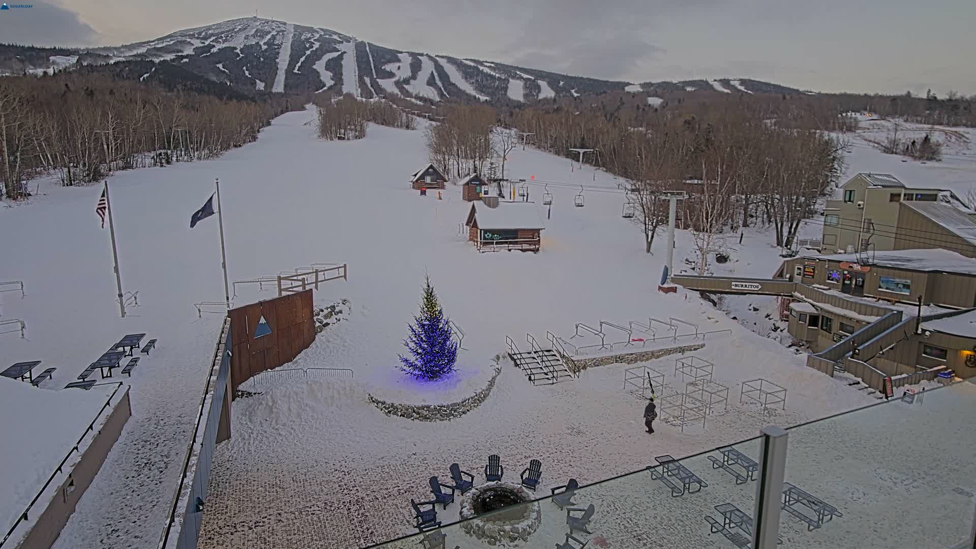 A clear, cold winter night scene at a snow-covered mountain ski resort reveals illuminated slopes, multiple buildings, and ski lifts under a starry sky.