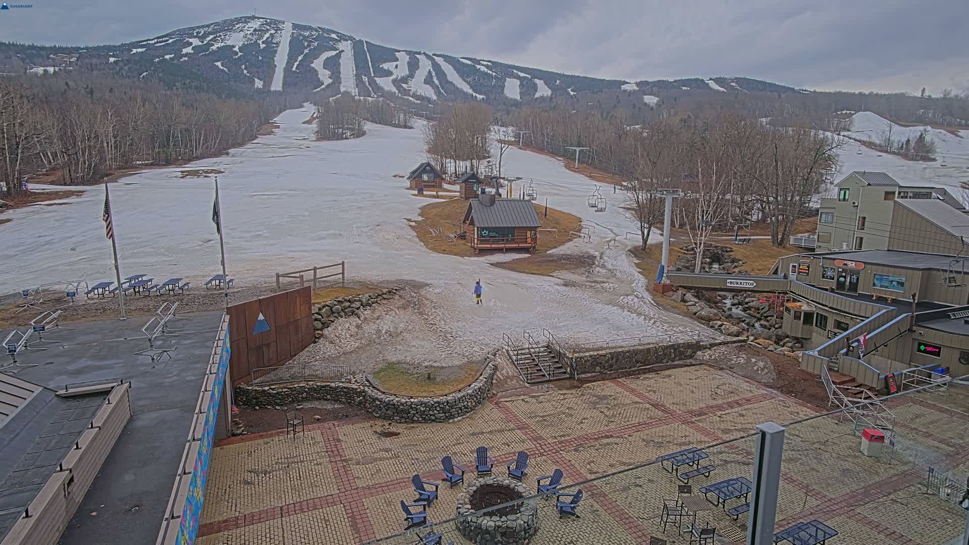 A clear, cold winter night scene at a snow-covered mountain ski resort reveals illuminated slopes, multiple buildings, and ski lifts under a starry sky.