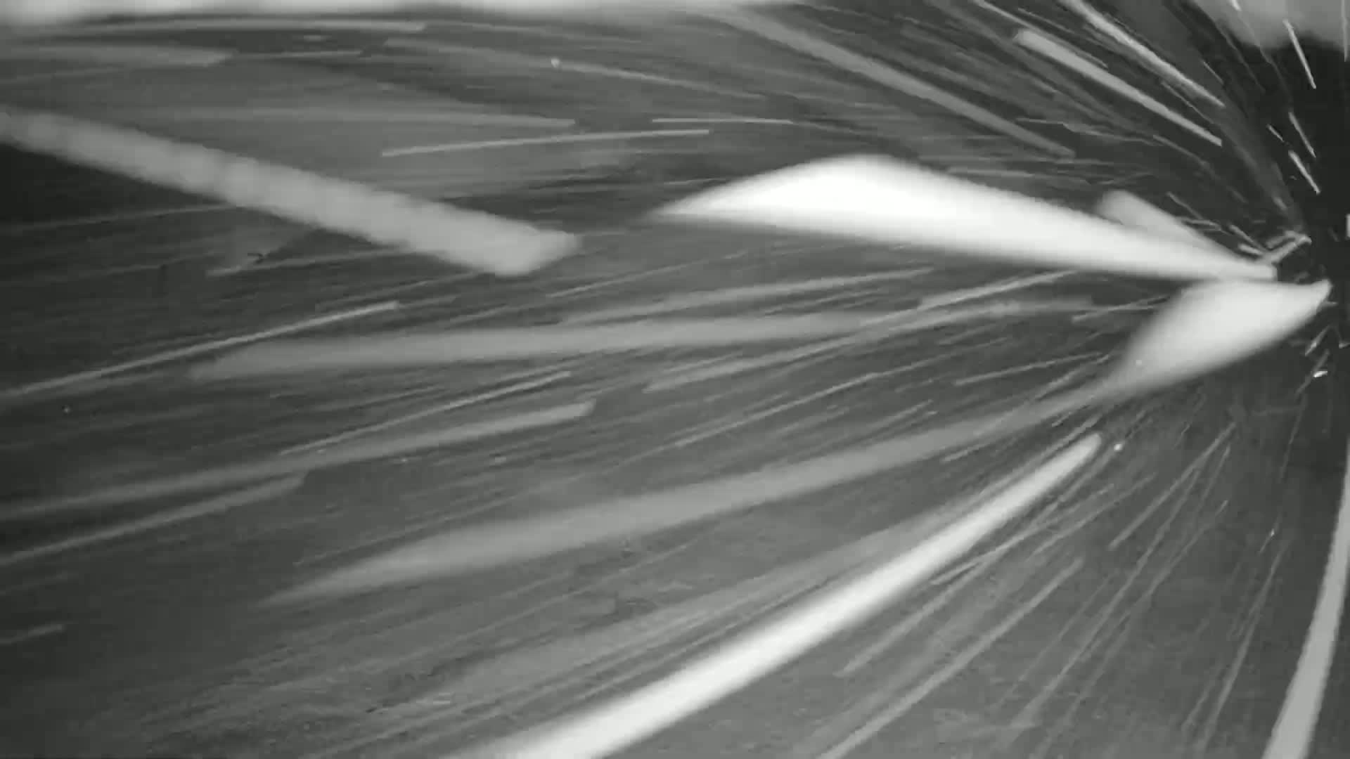 Heavy snow is falling, creating streaks of white against a dark background as seen from a moving vehicle.