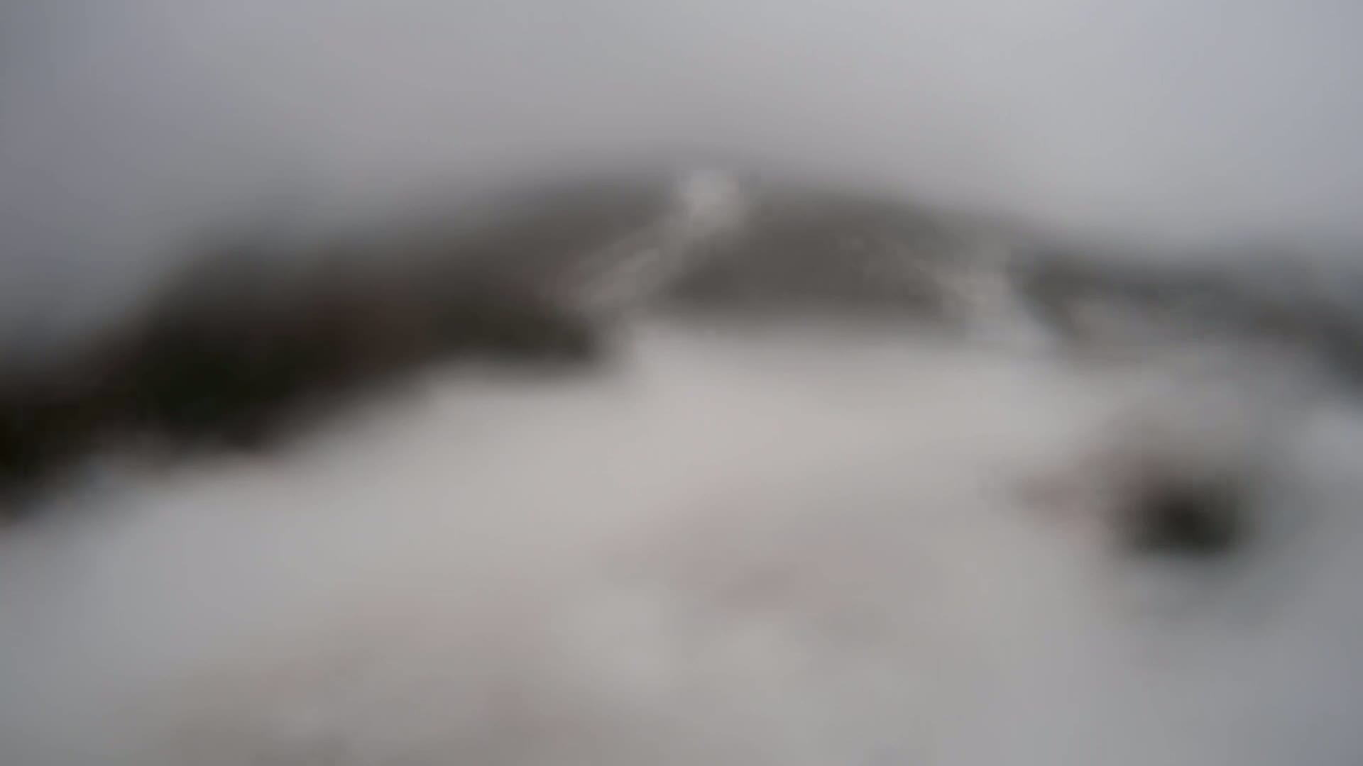 A blurry image shows a dark, indistinct landmass shrouded in heavy fog.