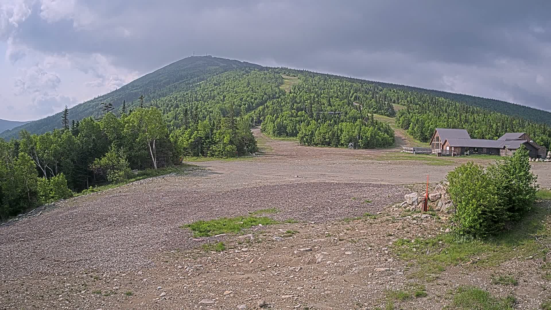 A large, grassy mountain with a ski resort at its base under a partly cloudy sky.